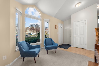 Sitting room featuring vaulted ceiling, a textured ceiling, light carpet, and light wood-type flooring