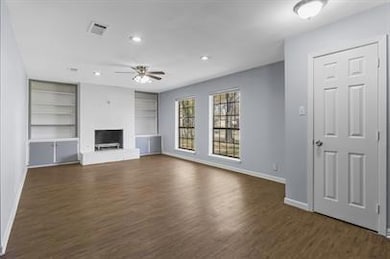 Unfurnished living room with ceiling fan, dark har