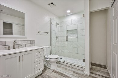 Bathroom with vanity, a stall shower, wood finishe