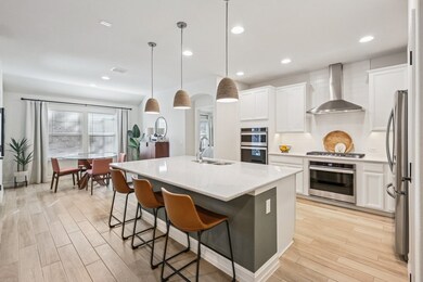 Kitchen featuring a large island, pendant lights, decorative backsplash, wall stainless vent hood, recessed lighting, and white cabinets