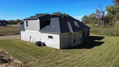 View of side of property featuring a yard, brick siding, and roof with shingles