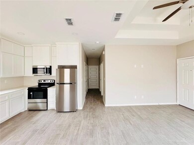 Kitchen featuring appliances with stainless steel finishes, ceiling fan, white cabinetry, and light wood-type flooring