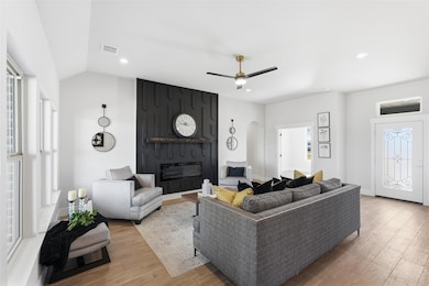 Living room featuring a large fireplace, light wood-type flooring, recessed lighting, ceiling fan, and arched walkways