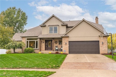 View of front of house featuring a shingled roof, covered porch, driveway, brick siding, and a chimney