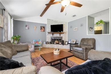 Living room featuring wood finished floors, a ceiling fan, and a fireplace