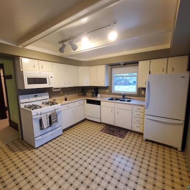 Kitchen featuring sink, white cabinets, white appl