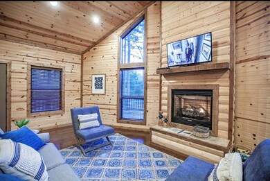 Living area featuring wooden ceiling, wood walls, wood finished floors, a fireplace with raised hearth, and lofted ceiling
