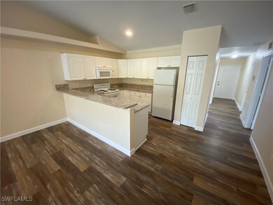 Kitchen with white appliances, a peninsula, white