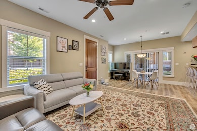 Living room with light wood-type flooring, recessed lighting, and a ceiling fan