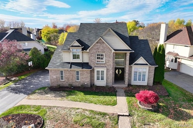 View of front of house with a shingled roof, brick siding, a front lawn, and driveway