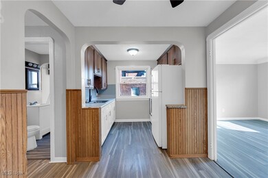 Kitchen with dark wood-style floors, freestanding refrigerator, a wainscoted wall, wooden walls, and light countertops