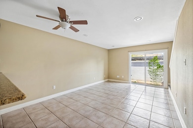 Spacious living area with tile flooring, recessed lighting, and natural light pouring in from sliding glass doors. Easy flow to the private patio—great for relaxing or entertaining!