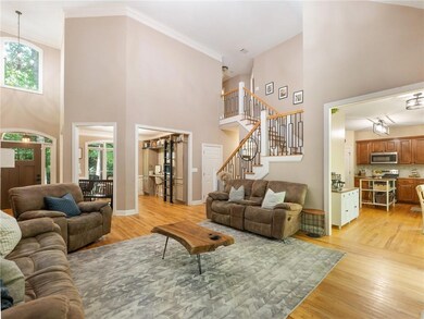 Living room featuring light wood finished floors, plenty of natural light, a high ceiling, ornamental molding, and stairs