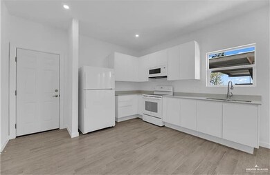 Kitchen with white appliances, white cabinets, light countertops, light wood-type flooring, and recessed lighting