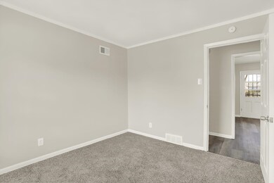 Empty room featuring dark carpet, baseboards, ornamental molding, and a smoke detector
