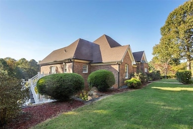 View of home's exterior with stairway, brick siding, a yard, and roof with shingles
