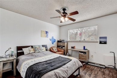 Bedroom with wood finished floors, a textured ceiling, and ceiling fan