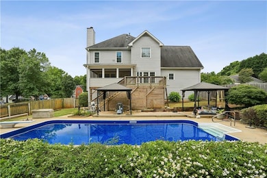 Rear view of house featuring a gazebo, stairs, a chimney, a fenced backyard, and a patio area