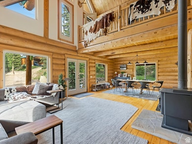Living area with high vaulted ceiling, a wood stove, light wood-style floors, french doors, and wooden ceiling