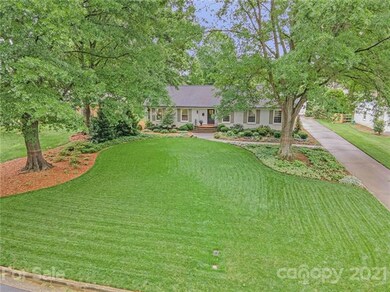 The front yard is big and flat, with stately trees