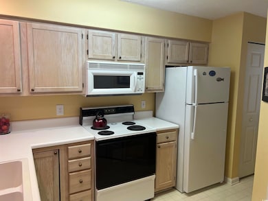 Kitchen featuring white appliances and light brown cabinetry