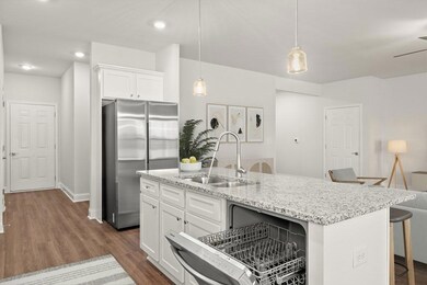 Kitchen featuring a sink, freestanding refrigerator, a kitchen breakfast bar, white cabinets, and dark wood-style floors