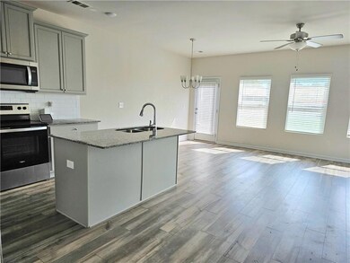 Kitchen with gray cabinets, a sink, light stone co