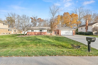 View of front of house with brick siding, a front lawn, concrete driveway, and an attached garage