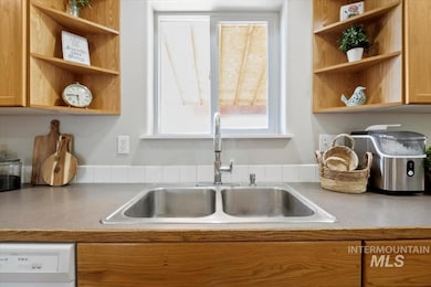 Kitchen with open shelves, white dishwasher, and light countertops