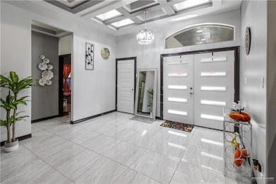 Entryway featuring coffered ceiling, beamed ceiling, a high ceiling, french doors, and a notable chandelier