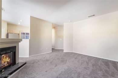 Unfurnished living room featuring carpet flooring and a glass covered fireplace