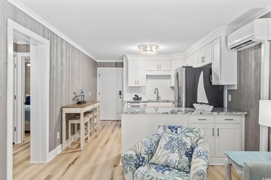Kitchen with white cabinetry, an AC wall unit, lig