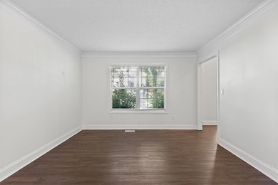 Empty room featuring dark wood finished floors and ornamental molding