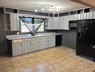 Kitchen featuring open shelves, black appliances, light countertops, and white cabinetry