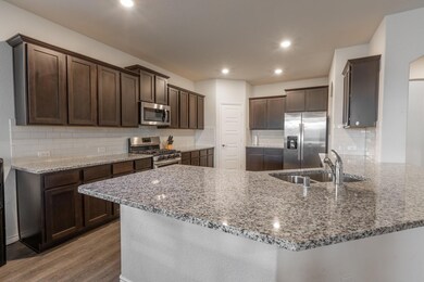 Kitchen with hardwood / wood-style floors, sink, appliances with stainless steel finishes, and backsplash