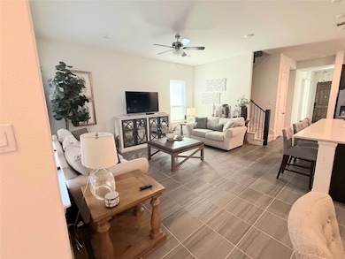 Living room featuring a ceiling fan and stairs
