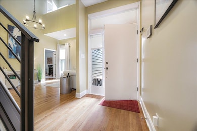 Foyer with stairs, light wood-style flooring, a chandelier, and a high ceiling