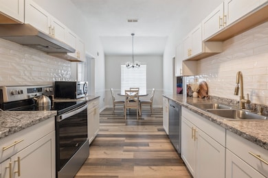 Kitchen with visible vents, white cabinets, dark w
