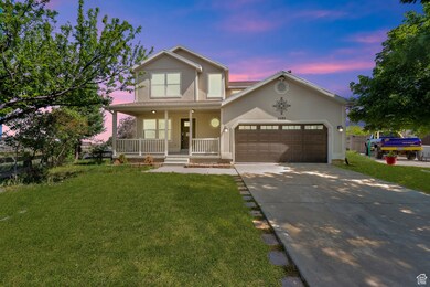 Traditional-style home featuring a porch, driveway, a front lawn, and stucco siding