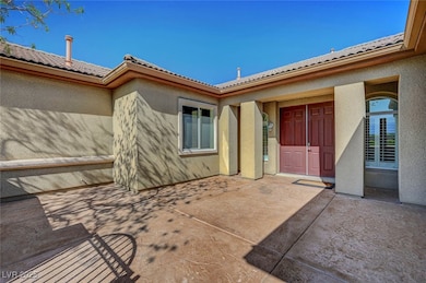 Property entrance featuring a tiled roof, a patio, and stucco siding