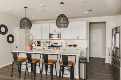 Kitchen featuring stainless steel appliances, decorative backsplash, white cabinetry, a kitchen bar, and a center island with sink