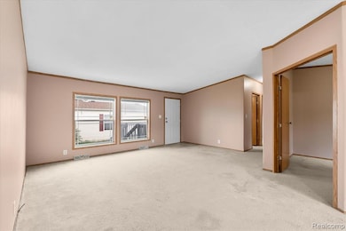 Carpeted empty room featuring crown molding and baseboards