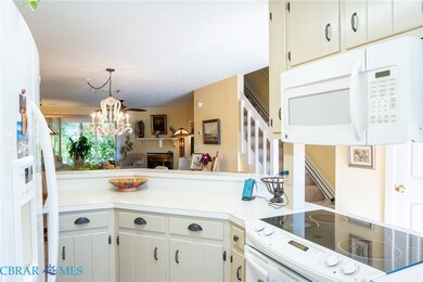 Kitchen featuring white appliances, light countertops, white cabinets, decorative light fixtures, and a fireplace