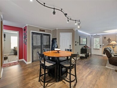 Dining room featuring wood finished floors, baseboards, crown molding, and rail lighting