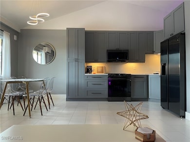Kitchen with lofted ceiling, gray cabinetry, and b