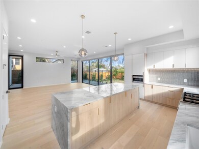 Kitchen featuring a center island, light wood-style floors, light brown cabinetry, open floor plan, and hanging light fixtures