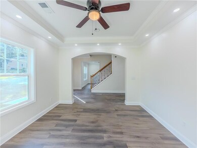 Unfurnished room featuring arched walkways, a tray ceiling, stairs, wood finished floors, and recessed lighting