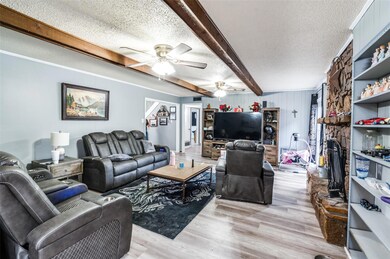 Living room with a textured ceiling, light hardwood / wood-style floors, and ceiling fan