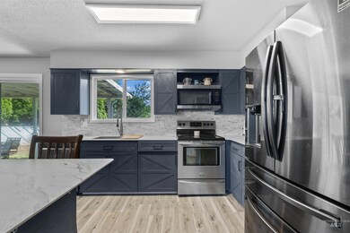 Kitchen featuring appliances with stainless steel finishes, backsplash, light wood-type flooring, and a textured ceiling