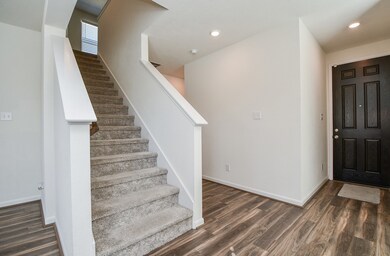 The simple, carpeted staircase sits just off the main hallway/foyer, naturally blending with the neutral color theme, durable wood-look tile, and sleek lines.